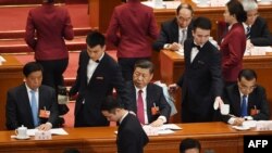 FILE - Chinese President Xi Jinping (C) looks on as his tea cup is replenished during the second plenary session of the National People's Congress in Beijing's Great Hall of the People on March 9, 2018.