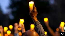 FILE - Marchers hold candles up as they listen to a speaker during a march and candlelight vigil for Ahmaud Arbery in the Satilla Shores neighborhood, in Brunswick, Ga., Feb. 23, 2021.