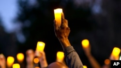 FILE - Marchers hold candles up as they listen to a speaker during a march and candlelight vigil for Ahmaud Arbery in the Satilla Shores neighborhood, in Brunswick, Ga., Feb. 23, 2021.