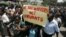 FILE - Zimbabwe's civil servants carry placards as they march during a protest in the streets of the capital Harare, Feb. 19, 2010. 