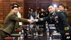 In this photo provided by the South Korea Defense Ministry, South Korean Maj. Gen. Kim Do-gyun, right, shakes hands with his North Korean counterpart Lt. Gen. An Ik San during a meeting in Panmunjom in the Demilitarized Zone. South Korean officials say they are considering suspending large joint military exercises with the U.S.