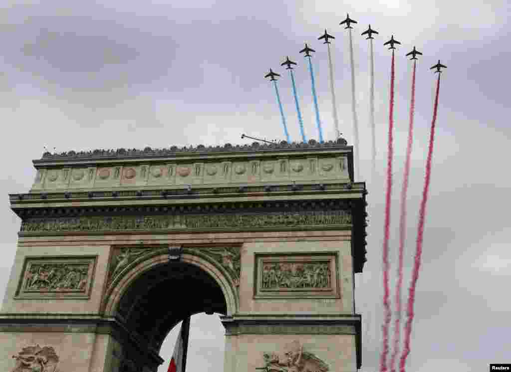 Warna-warna nasional Perancis tampak di udara di atas gerbang Arc de Triomphe dalam parade tradisional Hari Bastille di Champs Elysees, Paris (14/7).