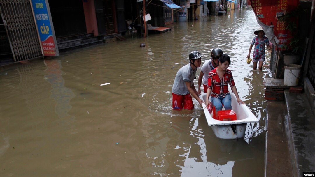 Men use a bathtub to ferry a woman on a flooded street caused by typhoon Kai Tak - RTR36XQY