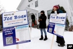 Pendukung kampanye tertulis Presiden Joe Biden berdiri di luar tempat pemungutan suara pada hari pemilihan pendahuluan presiden, 23 Januari 2024, di Holderness. (Foto: AP)