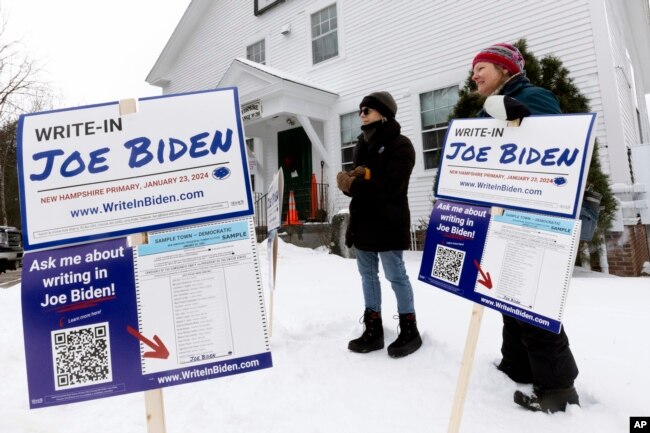 Pendukung kampanye tertulis Presiden Joe Biden berdiri di luar tempat pemungutan suara pada hari pemilihan pendahuluan presiden, 23 Januari 2024, di Holderness. (Foto: AP)