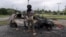 A man stands in front a burnt car after unrest in Noumea, New Caledonia, on May 15, 2024. France has imposed a state of emergency in the French Pacific territory.