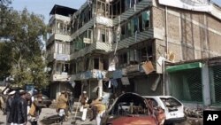 Afghan locals clears the debris near damaged vehicles outside the bank which was attacked on Saturday by Taliban insurgents in Jalalabad, east of Kabul, Afghanistan, February 20, 2011