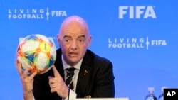 ARCHIVO - El presidente de la FIFA, Gianni Infantino, sostiene un balón de fútbol mientras habla durante una conferencia de prensa después de la reunión del Consejo de la FIFA, el viernes 15 de marzo de 2019, en Miami.