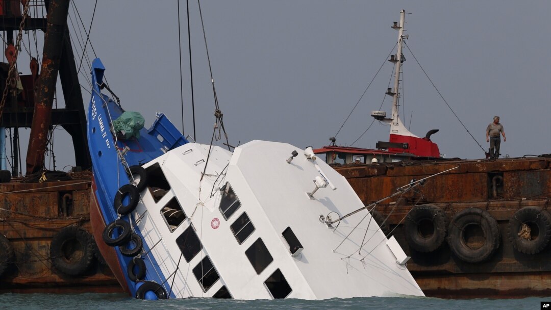Para petugas berusaha mengangkat kapal ferry yang tenggelam di Pulau Lamma, Hong Kong (2/10).
