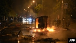 巴黎西郊楠泰尔防暴警察站在一辆被骚乱者点燃的汽车旁。（2023年6月28日，法新社） 