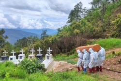 Health workers in protective suit carry a coffin with the body of a COVID-19 victim during a burial at a cemetery in Falam township in western Myanmar's Chin state, June 21, 2021. (Credit: Chinland Herald Daily News)