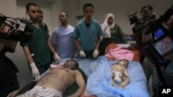 Madaktari wa Libya wakionyesha maiti za mtu mmoja na mtoto zilizokutwa katika nyumba inayosemekana ilishambuliwa na NATO Jumapil 19, 2011 mjini Tripoli.