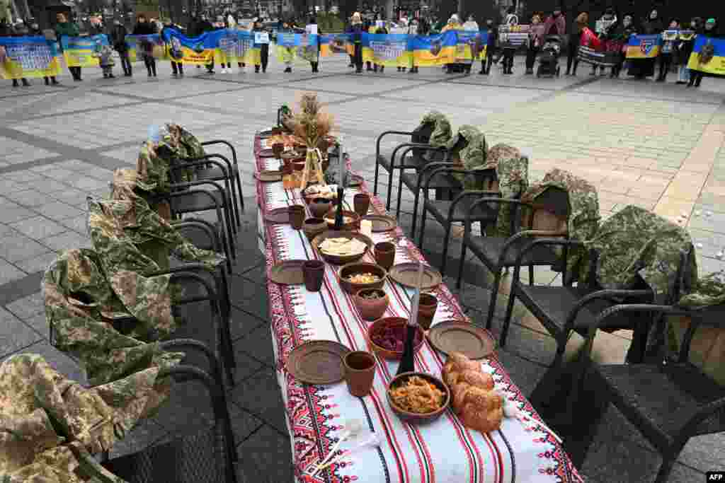 Soldiers&#39; uniforms hang on empty chairs next to a symbolic Christmas table set with traditional dishes as people attend a rally in support of prisoners of war and missing soldiers in Lviv, Ukraine, Dec. 21, 2024.