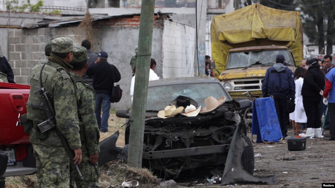 Tentara, warga setempat dan angora tim forensik berdiri di depan tempat ledakan di desa Yesus Tepactepec, dekat ibukota negara bagian Tlaxcala (15/3).