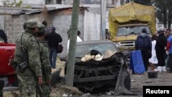Tentara, warga setempat dan angora tim forensik berdiri di depan tempat ledakan di desa Yesus Tepactepec, dekat ibukota negara bagian Tlaxcala (15/3).