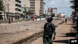 Un officier de police regarde les manifestants, alors qu'ils continuent de lancer des pierres et de bloquer les routes lors de manifestations de masse après la publication des résultats préliminaires à Conakry le 23 octobre 2020.