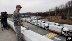 Seorang tentara Amerika mengamati arus kendaraan Korea Selatan yang kembali dari kompleks perindustrian di Kaesong, Korea Utara dari kantor pabean, imigrasi dan karantina dekat zona demiliterisasi (28/3).