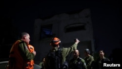 نیروهای امدادرسان اسرائیل در محل برخورد موشک در رمت گن در حومه تل‌آویو، پس از حملات موشکی بامداد شنبه از میدأ ایران