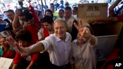 Vice President Salvador Sanchez, presidential candidate for the ruling Farabundo Marti National Liberation Front (FMLN) and his wife Margarita Villalta pose for photos after voting at a polling station in San Salvador, El Salvador, Feb. 2, 2014.