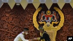 In this photo released by Malaysia's Department of Information, King Sultan Abdullah Sultan Ahmad Shah, right, receives documents from Prime Minister Muhyiddin Yassin during the parliamentary session in Kuala Lumpur, May 18, 2020.