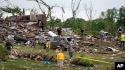 Para pekerja memeriksa rumah yang hancur akibat diterpa angin puting beliung di Greenfield, Iowa, 21 Mei 2024. (AP/Charlie Neibergall)