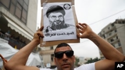 Seorang pendukung Hizbullah menunjukkan poster pemimpin Hizbullah, Sayyed Hassan Nasrallah, dalam sebuah unjuk rasa di Aukar, timur laut Beirut, Lebanon, 10 Juli 2020. 