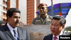 El presidente de China, Xi Jinping, habla con su homólogo venezolano Nicolás Maduro, frente a un busto de Hugo Chávez durante una visita a Caracas en 2014.