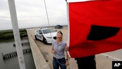 Fire Chief Ann Graham, left, and police officer Thomas Molino III raise a tropical storm warning flag, Sept. 13, 2018, in Isle of Palms, S.C.