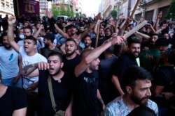 FILE - Shi'ite Hezbollah and Amal Movement groups stand in front of Lebanese army as they shout slogans against anti-government protesters, in downtown Beirut, Lebanon, June 6, 2020.