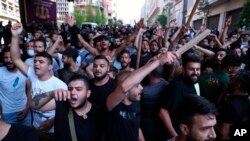 Shiite Hezbollah and Amal Movement groups stand in front of Lebanese army as they shout slogans against anti-government protesters, in downtown Beirut, Lebanon, Saturday, June 6, 2020. 
