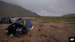 Migrantes de Ecuador solicitantes de asilo acampan para protegerse del viento y la lluvia mientras esperan el proceso, tras cruzar la frontera entre México y Estados Unidos, el 2 de febrero de 2024, cerca de Jacumba, California. 