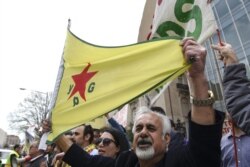A man holds a flag of YPG, a Syria-based Kurdish militant group, during a protest against Turkish President Recep Tayyip Erdogan in front of Brookings Institution in Washington, March 31, 2016, where President Erdogan was speaking.