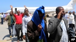 FILE- Deported Somali nationals gesture as they arrive at the airport in Somalia's capital of Mogadishu, April 9, 2014. Sixty-eight Somalis arrived in Magodishu Friday, having been deported by U.S. immigration authorities.