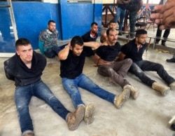 FILE - Suspects in the assassination of Haiti's President Jovenel Moise sit on the floor handcuffed after being detained, in Port-au-Prince, Haiti, July 8, 2021.