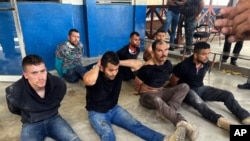 Suspects in the assassination of Haiti's President Jovenel Moise sit on the floor handcuffed after being detained, at the General Direction of the police in Port-au-Prince, Haiti, July 8, 2021. 