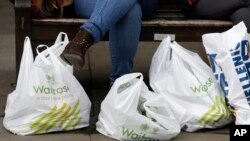 Tas-tas plastik penuh barang belanjaan dari supermarket diletakkan di lantai oleh seorang pembeli di London, 4 Juni 2014. (Foto: dok). Coles, salah satu jaringan supermarket di Australia, menuai kecaman dari para pecinta lingkungan karena membatalkan keputusan yang seharusnya menghentikan penyediaan kantong plastik kepada para pelanggannya.