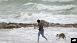 Tropical Weather: A woman runs in the heavy surf with her dog at Sunset Beach in Treasure island, Fla., Monday, June 6, 2016, as Tropical Storm Colin churns in the Gulf of Mexico. Colin was expected to make landfall somewhere along Florida's gulf coast.