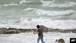 Tropical Weather: A woman runs in the heavy surf with her dog at Sunset Beach in Treasure island, Fla., Monday, June 6, 2016, as Tropical Storm Colin churns in the Gulf of Mexico. Colin was expected to make landfall somewhere along Florida's gulf coast.