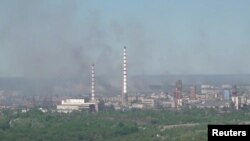 Asap hitam tampak mengepul sementara pasukan Rusia membombardir pabrik kimia di Sievierodonetsk, Ukraina timur hari Minggu (12/6). 