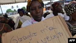 Une victime de la crise post-électorale 2010 tient une pancarte avec la mention "Gbagbo m'a transformé en une veuve" lors d'un rassemblement dans le quartier populaire de Kouassai Abidjan, le 28 février 2013.