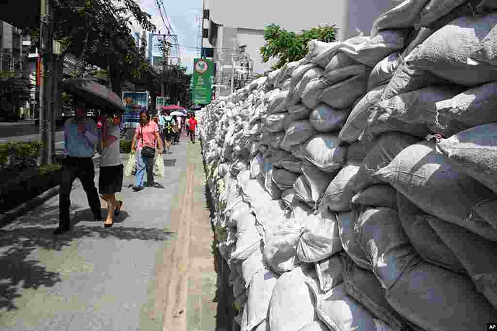 A wall of sandbags built on Bangkok's busy Phahonyothin Road as office workers walk past, October 27, 2011. (VOA - D. Schearf)