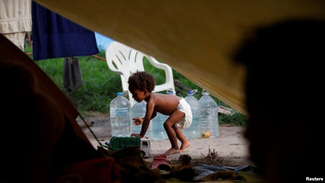 El solicitante de asilo Natanael, de 1 año, cuya madre es venezolana pero nació en Colombia, juega con un carrito de juguete junto a su tienda de campaña en un campamento improvisado, en Matamoros, México 20 de junio de 2023