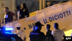 FILE - A migrant disembarks escorted by police from Italy's Diciotti coast guard vessel carrying 67 asylum seekers berthed at Trapani port on July 12, 2018. 