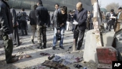 An Afghan cameraman films the vest of an attacker and arms collected from the scene of a suicide attack in Kabul, Afghanistan, ,November 21, 2012. 