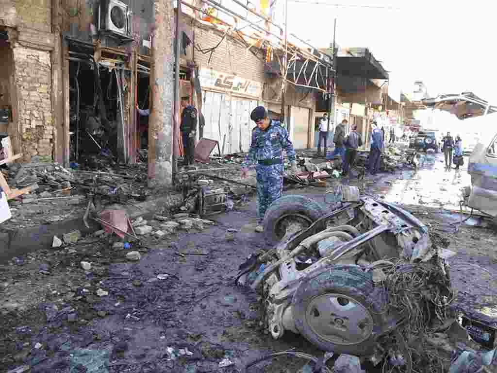 Pasukan keamanan Irak menyelidiki lokasi serangan bom di Hilla, sebelah selatan Baghdad (Reuters).