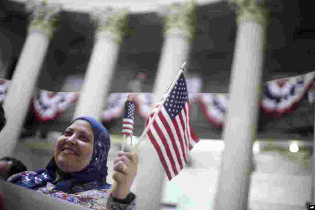 Fatma Atia, yang berasal dari Mesir dan tinggal di New York, melambaikan bendera Amerika dalam upacara pemutihan di kantor Federal, New York (22/3). (AP/Mary Altaffer)