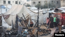 Palestinians survey the damage at the site of an Israeli strike on tents sheltering displaced people, amid the Israel-Hamas conflict, at Al-Aqsa Martyrs hospital in Deir Al-Balah in the central Gaza Strip, Oct. 14, 2024.