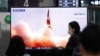 Arhiva - Ljudi gledaju TV program na kome se vidi fotografija severnokorejske nove vodeće rakete, tokom emisije vesti, na železničkoj stanici u Seulu, Južna Koreja, 26. marta 2021.