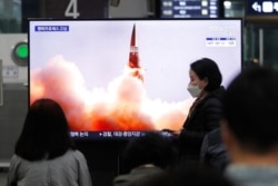 FILE - People watch a TV showing an image of North Korea's new guided missile during a news program at the Suseo Railway Station in Seoul, South Korea, March 26, 2021.