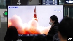 FILE - People watch a TV showing an image of North Korea's new guided missile during a news program at the Suseo Railway Station in Seoul, South Korea, March 26, 2021. 